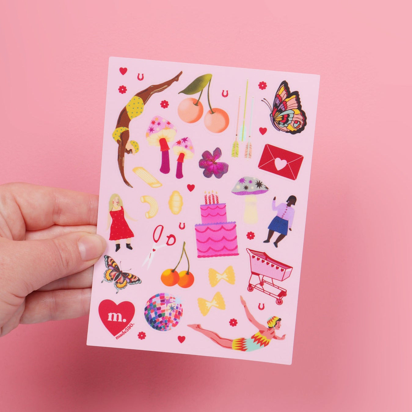Hand holding a colorful sticker sheet against a pink background