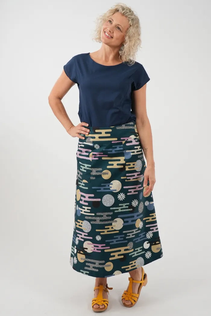 A woman modeling a navy blue short-sleeve top and a dark teal midi skirt with a colorful abstract pattern 