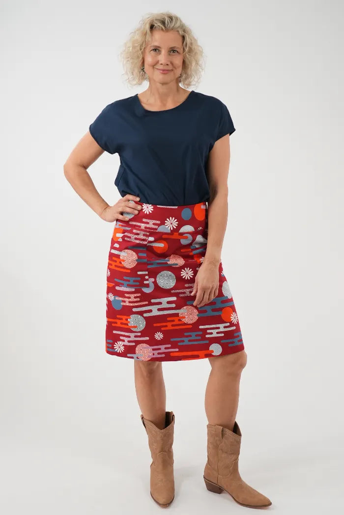 A woman modeling a red and blue patterned A-line skirt with a navy blue t-shirt 