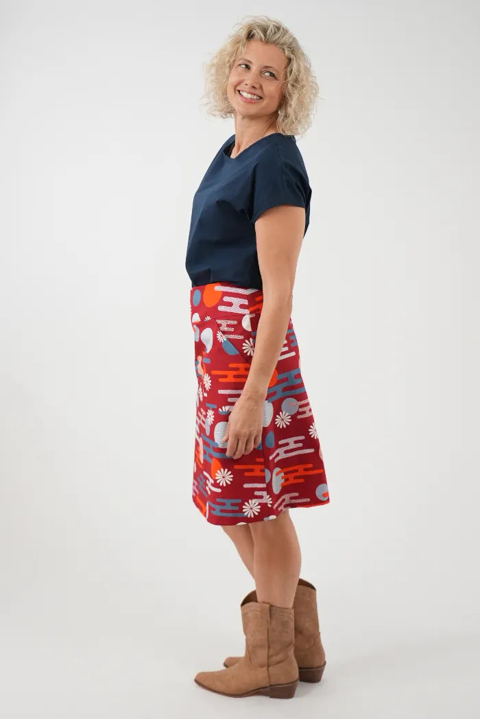 A woman modeling a red A-line skirt with a colorful retro abstract pattern, 