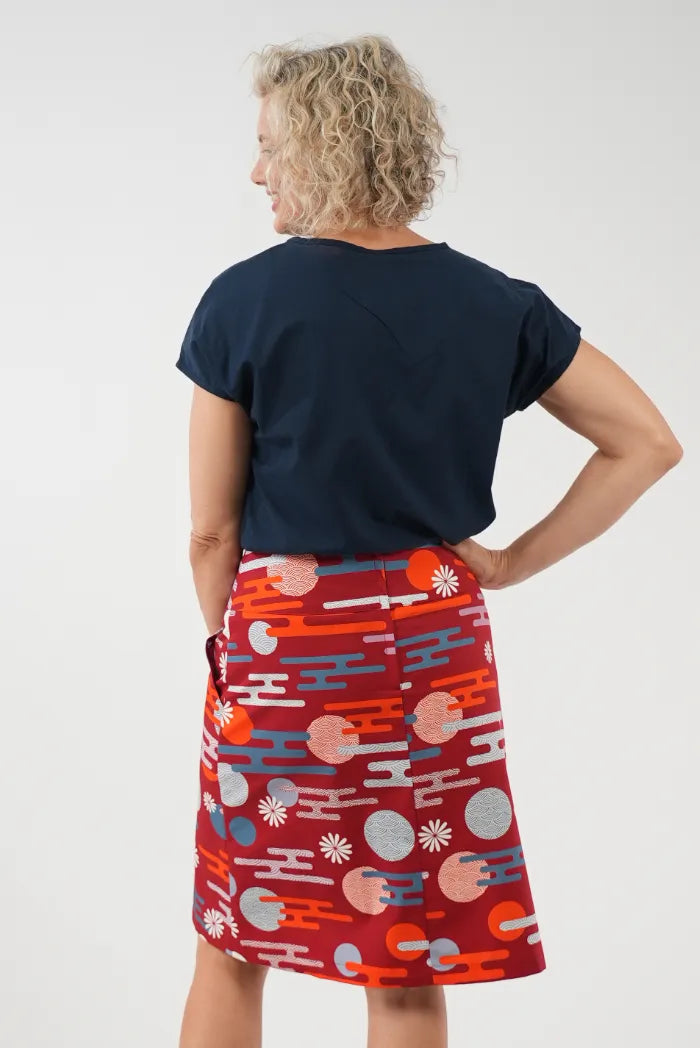 A woman shown from the back wearing a navy blue t-shirt and a red A-line skirt with 