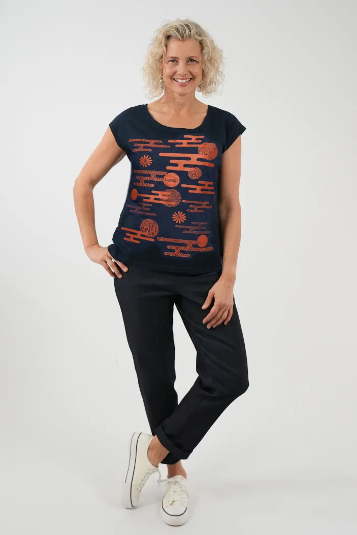 A woman modeling a navy blue short-sleeve t-shirt with a rust-orange abstract pattern, 